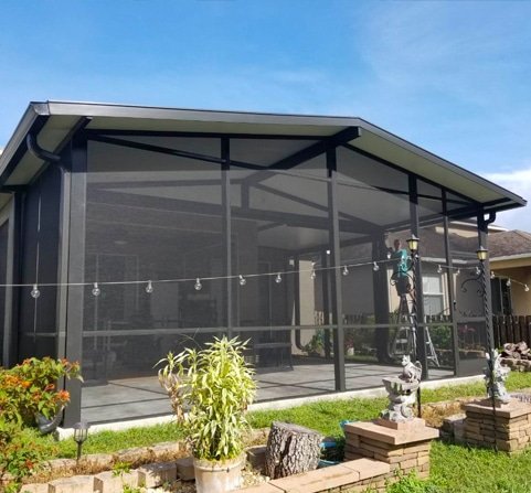 Patio enclosure repair in Titusville, FL with technician fixing screened structure